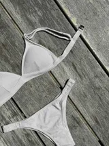 Conjunto de bikini turquesa con corpiño triangular de corte fijo, breteles regulables y almohadillas desmontables, y bombacha vedetina con frunce elástico en los costados.