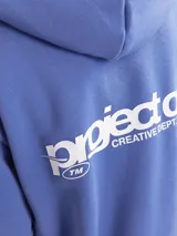 Buzo con capucha azul con estampado en el pecho que dice "project core creative dept. unlimited edition sourced and produced by jack&jones 1990".