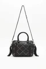 Cartera negra de cuero vacuno con correa desmontable, doble asa corta y cierre superior. Diseño matelassé con tachas metálicas plateadas y doradas en el frente y laterales con cierre.