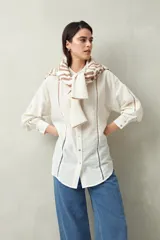 Camisa blanca de lino con botones de nácar, corte recto, cuello clásico y mangas largas con puños abotonados. Presenta detalles de calados tipo vainillas en el frente y las mangas.