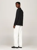 Camisa negra de viscosa con corte amplio, cuello inglés, tapeta de botones oculta, puños abotonados y logo metálico en la manga.