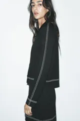 Chaqueta corta negra de punto con cuello solapa, manga larga y cierre frontal con botones.