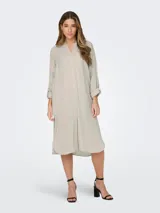 Vestido camisero largo color beige, de lino, con cuello camisero, abotonado al frente y mangas largas con puños abotonados.