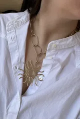 Collar dorado con cadena de eslabones grandes y dije en forma de sol.