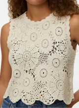 Top sin mangas color blanco roto, tejido a crochet con diseño de círculos concéntricos y bordes festoneados.