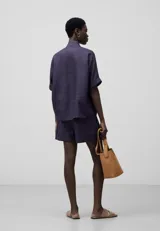 Bermuda corta de ramio a rayas verticales en tonos azul y rojo. Presenta cinturilla elástica en la espalda, pinzas en el delantero, bolsillos laterales y bajo con vuelta.