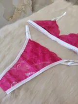 Conjunto de lencería fucsia de encaje floral, compuesto por un corpiño triangular sin aro y una tanga con tiras finas blancas.