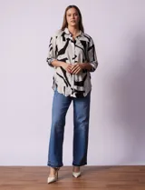 Camisa de manga larga con estampado abstracto en tonos verde y blanco. Cuello con solapa y abertura central con botones. Largo de manga regulable con presilla y botón. Terminación de ruedo anudada opcional.