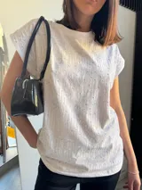 Remera blanca de algodón con cuello redondo y mangas cortas con strass plateado formando líneas verticales.