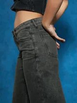 Jean de mezclilla color gris oscuro, de tiro alto y corte ancho (wide leg) que cae recto hasta el tobillo.