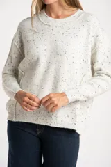 Sweater de punto color gris melange con efecto tweed o salpicado en negro, de calce oversize y cuello redondo.