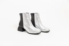 Botas cortas de cuero plateado y negro con punta cuadrada y taco geométrico.