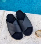 Sandalias negras con tiras cruzadas de cuero sintético y suela plana.