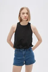 Blusa blanca de algodón sin mangas, con cuello a la base, abertura en la espalda y lazo ajustable.