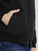 Campera bomber negra Calvin Klein con diseño acolchado en forma de rombos, cierre frontal con cremallera, cuello, puños y dobladillo acanalados, bolsillos laterales y bolsillo con cremallera en la manga izquierda.
