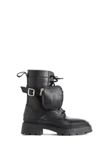 Borcego negro de cuero con base de goma track y detalle de bolsillo con cierre en el lateral.
