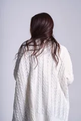 Saco tejido color crema con diseño de ochos y bolsillos frontales.