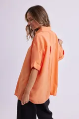 Camisa naranja fluida de manga corta con cuello clásico y cierre con botones.