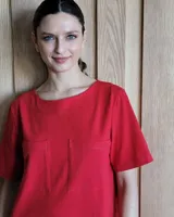 Vestido midi negro con cuello redondo y mangas cortas. Presenta dos bolsillos cuadrados en el pecho y ribetes blancos en cuello, mangas, bolsillos y ruedo.