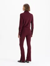 Pantalón de pierna recta color bordó, confeccionado en viscosa con elastano. Presenta cintura elastizada, costuras decorativas en el frente y broches metálicos con logo grabado en las botamangas.