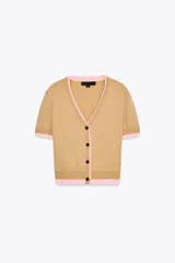 Cárdigan color beige de tejido de punto, con escote en pico, manga corta y cierre frontal con botones. Presenta ribete rosa en el cuello, el borde de las mangas y el bajo.