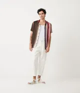Pantalón balloon de algodón y viscosa a rayas verticales en tonos marrón, beige, rosa y bordó. Tiene cintura elástica, cierre con botón y cremallera, bolsillos delanteros y traseros, y recortes.