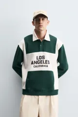 Polo relaxed fit verde oscuro con detalles en blanco, cuello solapa con cierre frontal de botonadura y manga corta. Bordado frontal con la inscripción "Los Angeles California".
