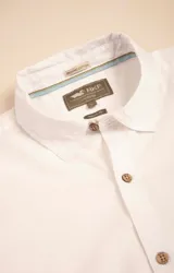 Camisa de manga larga color blanco, confeccionada en 100% algodón orgánico, con diseño liso y detalles de botones de madera.