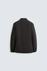 Blazer negro de corte relaxed fit, confeccionado en tejido de algodón con acabado ligeramente encerado. Tiene cuello con solapas de muesca, manga larga con puños abotonados, bolsillo de vivo en el pecho, bolsillos de solapa en la cadera, bolsillo interior, aberturas en la espalda y cierre frontal con botones.