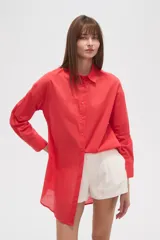 Camisa blanca de algodón con cuello clásico, corte holgado, cierre frontal con botones y mangas largas.