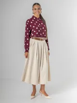 Falda midi de corderoy color beige claro, con pliegues verticales marcados y cintura elastizada. Incluye un cinturón desmontable de cuero marrón con hebilla dorada.