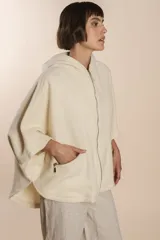 Capa color crudo de lana fina sin teñir, con capucha, cierre frontal y bolsillos con cierre.