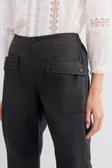 Pantalón babucha negro de lyocell satinado, con elástico en la botamanga, bolsillos plaqué con remaches metálicos y bolsillos cargo en las piernas.