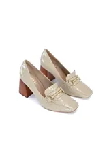 Zapato tipo mocasín color beige con estampado de cocodrilo, detalle de hebilla dorada y taco geométrico de madera.