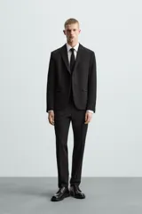 Pantalón de vestir azul marino, de corte slim fit, con bolsillos laterales y traseros. Se ajusta a la cintura con cinturón de cuero marrón.