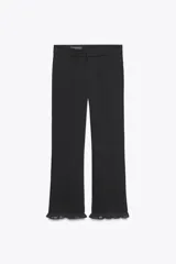 Pantalón negro de tiro alto con corte mini flare y volantes con estampado de lunares en el bajo.