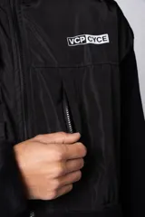 Campera negra con la parte superior de tela tipo rompevientos con dos bolsillos con solapa y la parte inferior de micro polar. Tiene cierre frontal y cuello alto.