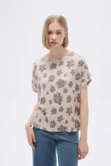 Remera blanca con estampado floral en color lila, de corte holgado y mangas cortas.