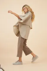 Capa amplia color marrón con capucha, cierre metálico y bolsillos delanteros. Espalda con canesú y botones laterales para generar la manga.