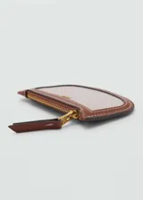 Monedero pequeño de tela color beige con borde de cuero marrón, cierre de cremallera y logo MNG dorado en el frente.