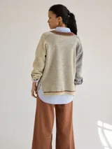 Buzo de punto con diseño texturizado en tonos beige y marrón, cuello con detalle negro y corte holgado.