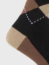 Calcetines de vestir para hombre, largo medio, con diseño de rombos (argyle) en colores negro, marrón y beige, con un pequeño logo de perro (Hush Puppies) bordado en el tobillo.