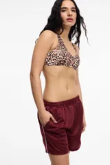 Short deportivo color bordó de tela satinada con cintura elastizada, bolsillos laterales y franja lateral blanca.