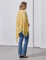 Poncho blanco de tejido calado con lurex, terminación asimétrica y cuello redondo.