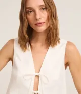 Chaleco blanco sin mangas con lazo delantero.