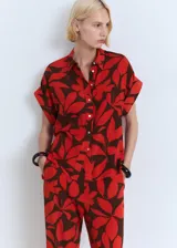 Pantalón de viscosa con estampado de hojas rojas sobre fondo marrón, corte recto, cintura elástica y bolsillos laterales.