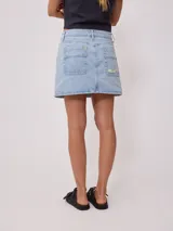 Minifalda de jean azul con bolsillos delanteros y traseros, tiro alto y corte recto.