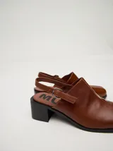 Mocasines color beige con taco bloque de madera color negro y correa trasera ajustable.