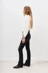 Pantalón de jean negro de corte flare con detalle de tachas metálicas en los bolsillos delanteros.