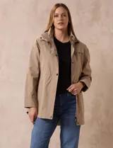 Campera impermeable color gris claro, marca Gallery. Tiene abertura central con cierre oculto y botones a presión, bolsillos delanteros y capucha plegable en el cuello.